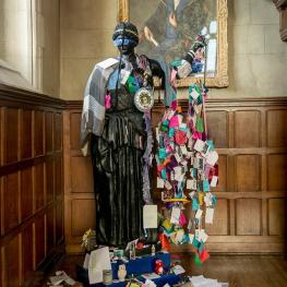 Statue of Athena covered in trinkets and paper chains.